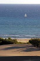 Sand dunes, sailing boat on the Mediterranean Sea in the background. Patara, Turkey.